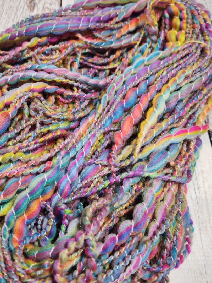 A "Strand of Rainbows" Hand-Spun Merino/Cashmere Art Yarn on a wooden table.
