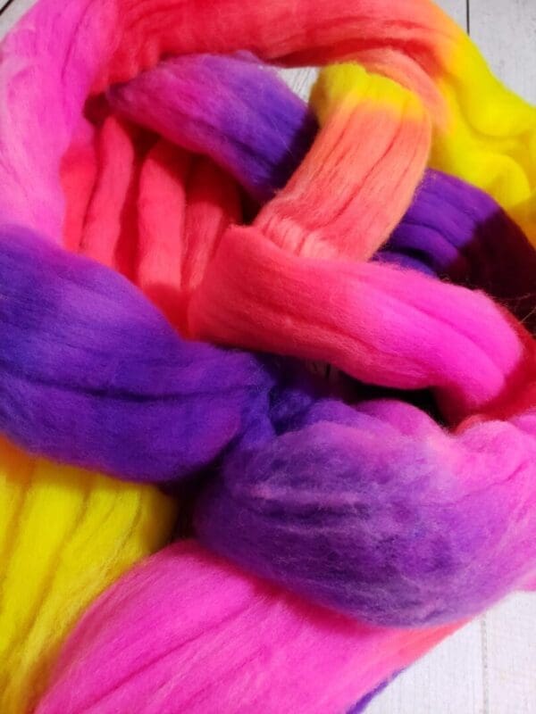 A colorful skein of Disco Date ~ 100g Hand-Dyed Luxury Combed Top Fiber on a wooden table.