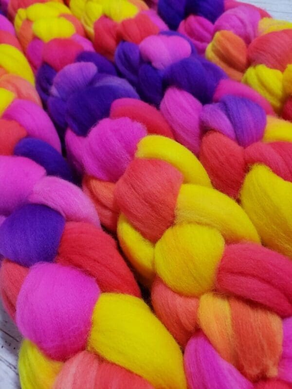 A bunch of Disco Date ~ 100g Hand-Dyed Luxury Combed Top Fiber laying on top of each other.