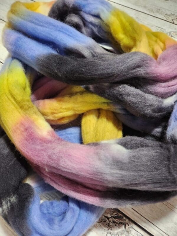 A bunch of colorful roving laying on top of a wooden table.