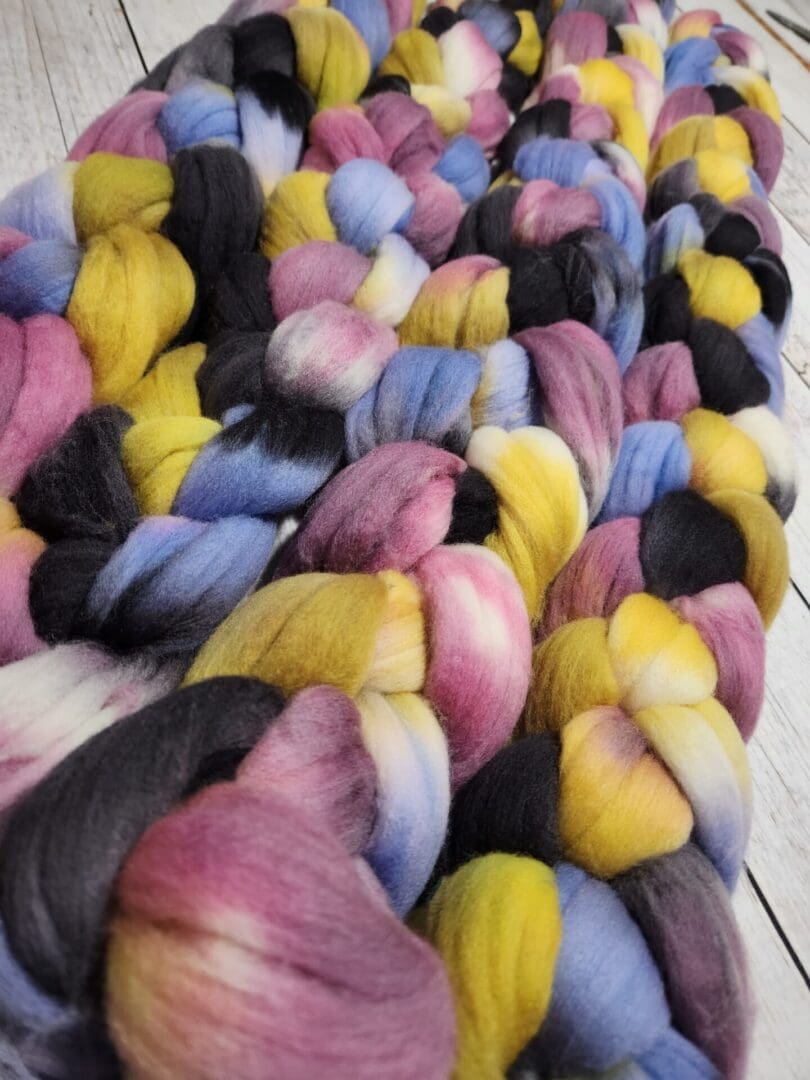 A skein of colorful roving on a wooden table.