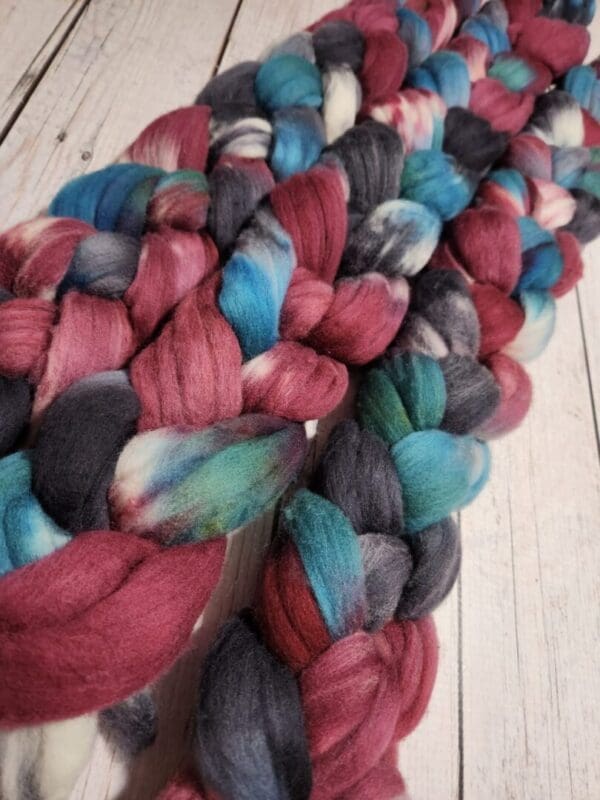 A skein of red, blue, and green roving on a wooden table.