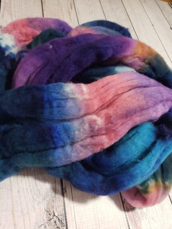 A pile of dyed fiber on a wooden floor.