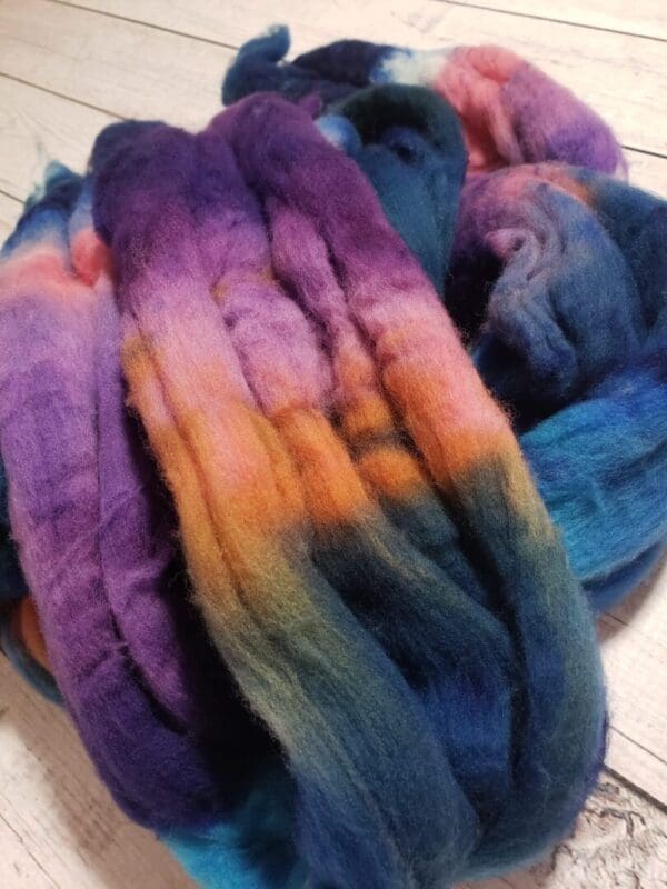 A skein of purple, blue, and orange roving.