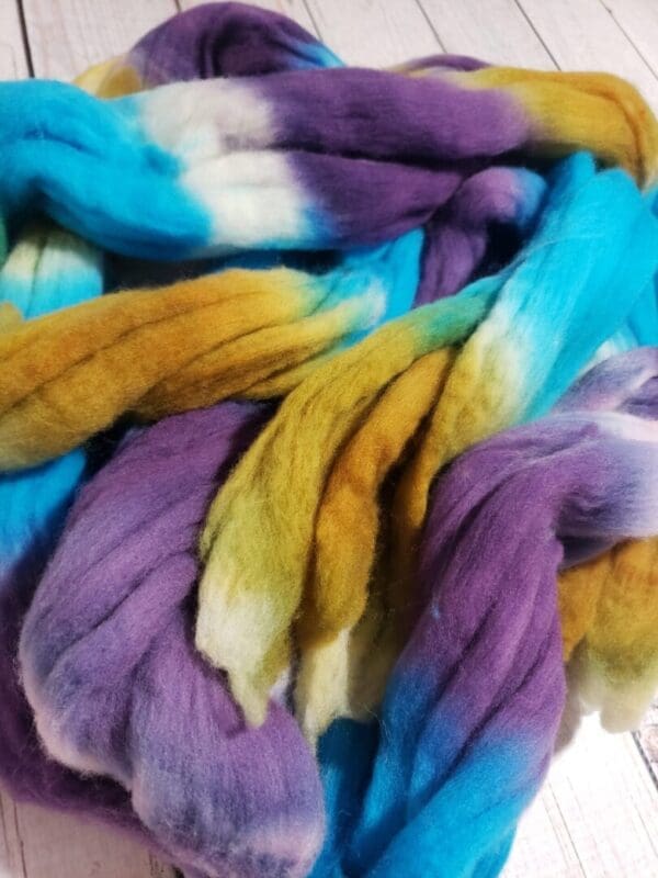 A pile of purple, blue, and yellow roving.