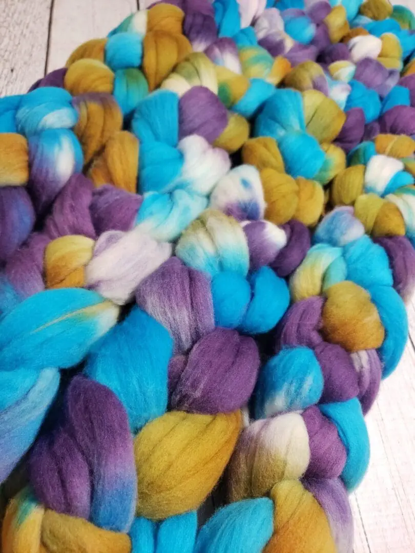 A pile of colorful roving on a wooden table.
