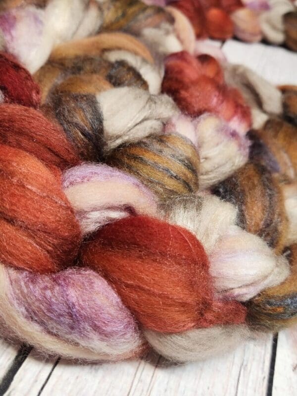 A close up of a red, orange and brown skein of roving.