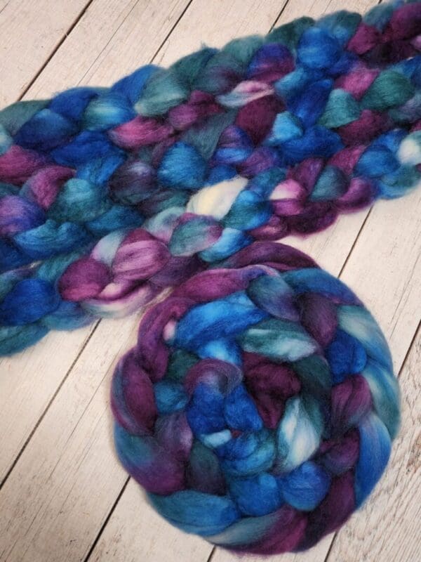 Purple and blue Disco Date ~ 100g Hand-Dyed Luxury Combed Top Fiber on a wooden floor.