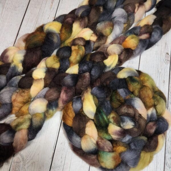 A bunch of Disco Date ~ 100g Hand-Dyed Luxury Combed Top Fiber on a wooden floor.