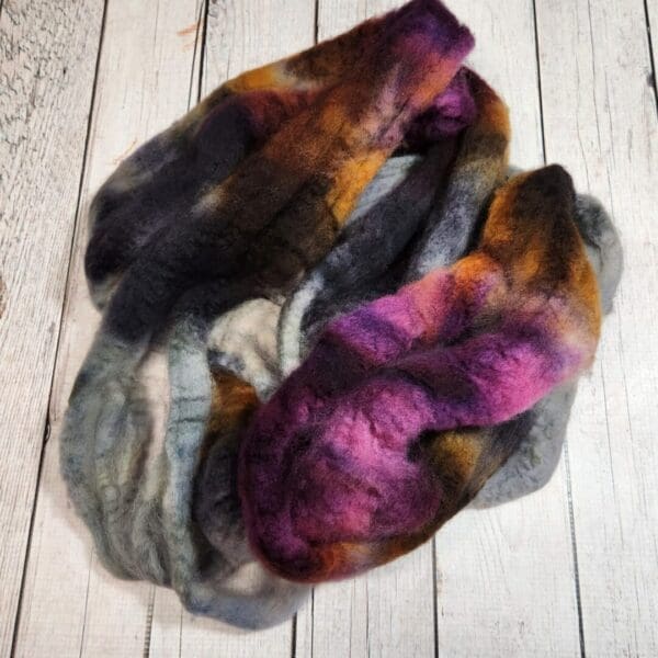 A Disco Date ~ 100g Hand-Dyed Luxury Combed Top Fiber made of purple, orange, and black wool.