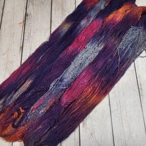 A skein of purple and orange yarn on a wooden floor.