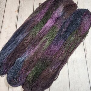 A skein of purple and green yarn on a wooden floor.