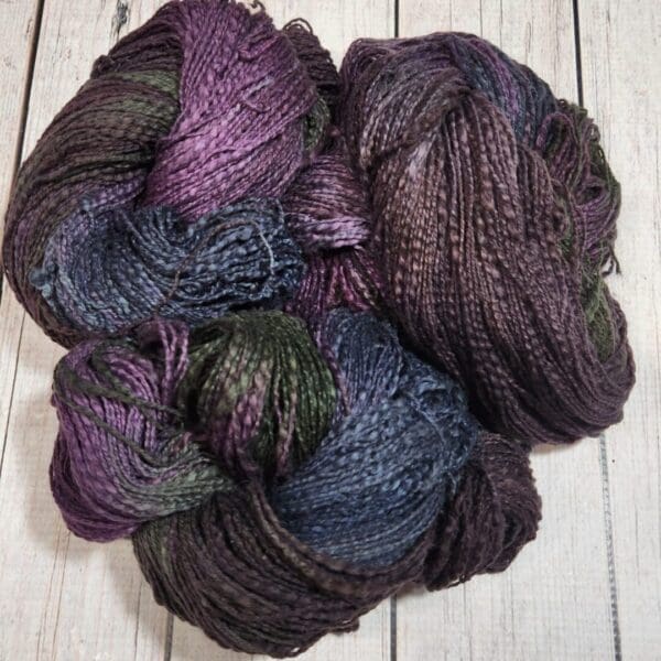 A skein of purple and blue yarn on a wooden table.