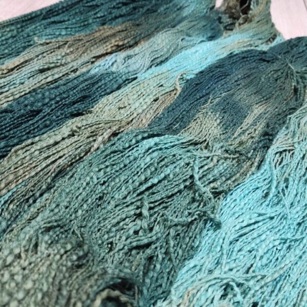 A close up of a blue and green yarn.