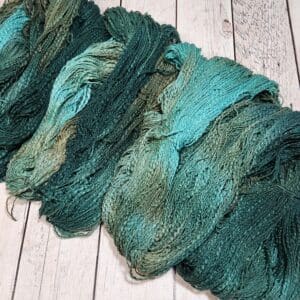 A skein of green and blue yarn on a wooden surface.