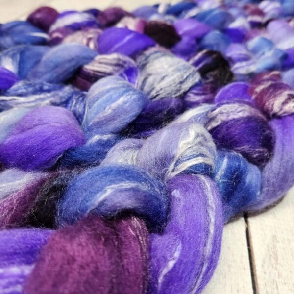 Purple and blue wool roving on a wooden floor.