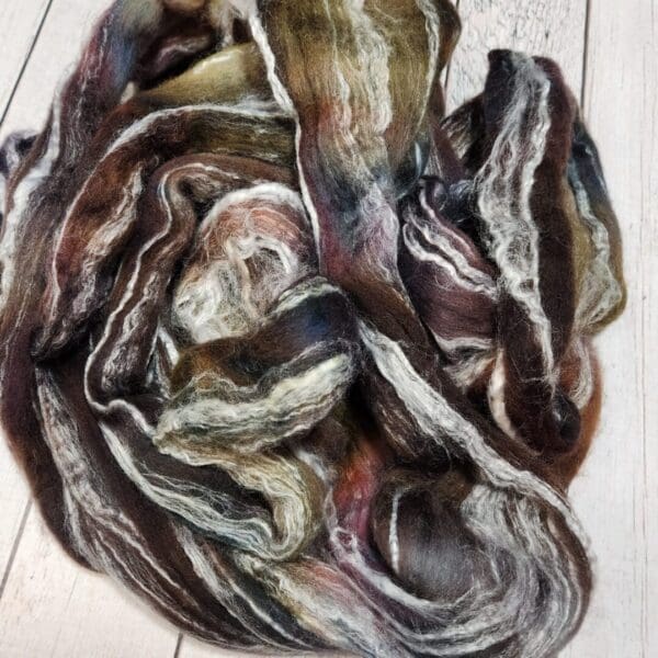 A skein of wool laying on top of a wooden floor.