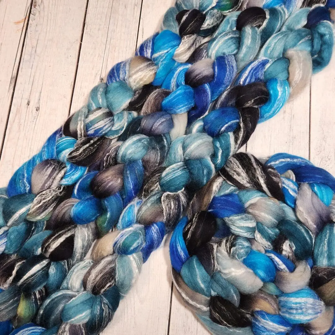 A bunch of blue and black yarn on a wooden table.