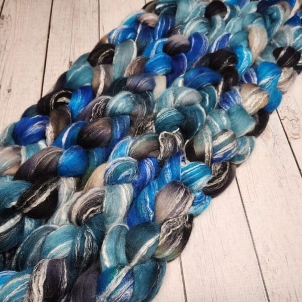 A skein of blue and black yarn on a wooden floor.