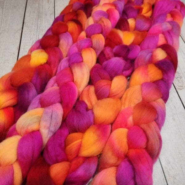 A pile of red, orange and yellow roving on a wooden table.