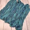 A skein of blue and green yarn on a wooden table.