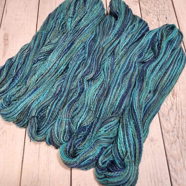 A skein of blue and green yarn on a wooden table.