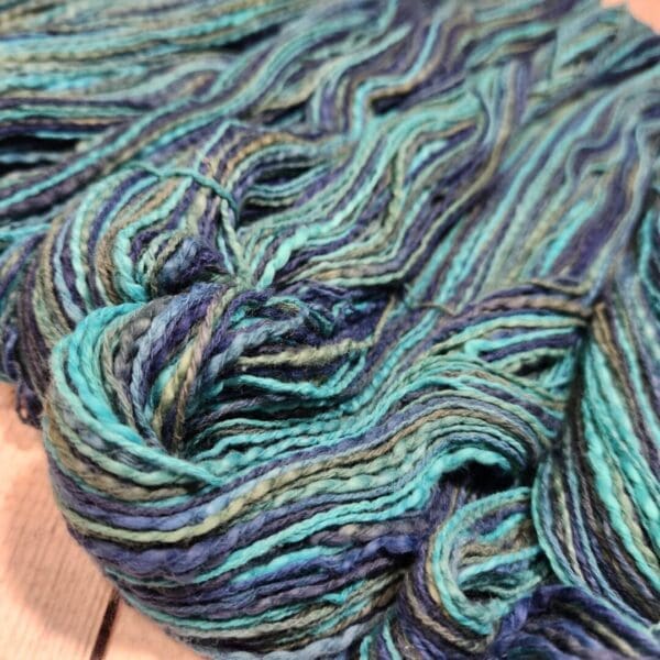 A skein of blue and green yarn on a wooden table.