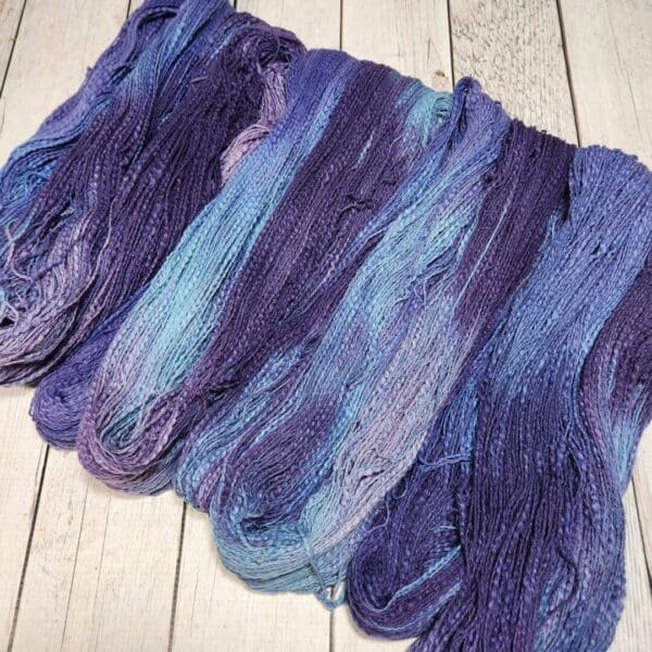 Purple and blue yarn laying on a wooden floor.