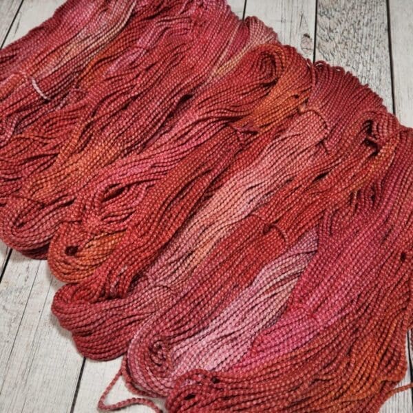 Skeins of red and orange yarn on a wooden table.