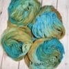 Four skeins of yarn on a wooden floor.