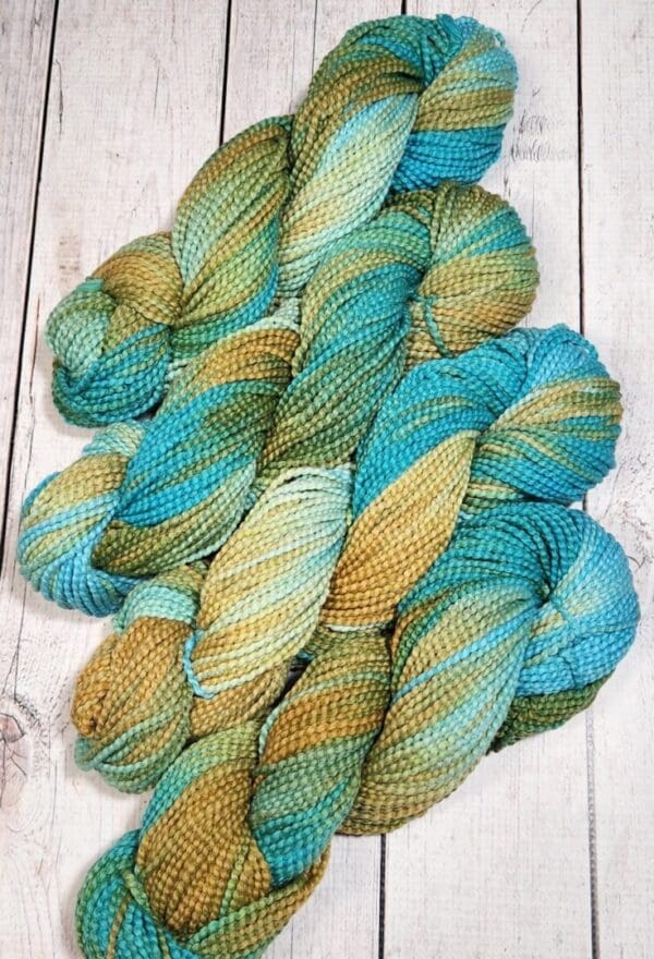 Four skeins of yarn in blue, green and yellow.