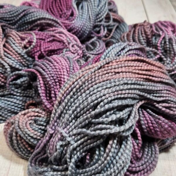 Skeins of purple and grey yarn on a wooden table.