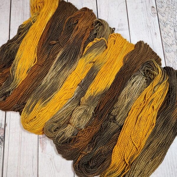 A bunch of yellow and brown skeins on a wooden floor.