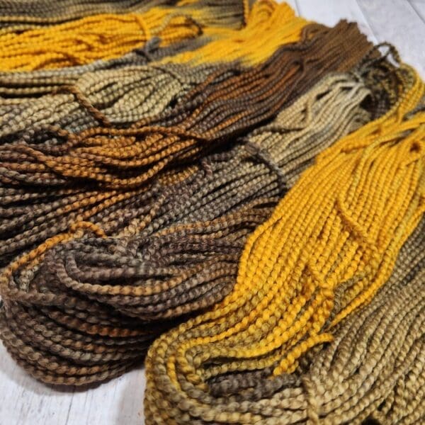 A bunch of yellow and brown yarns on a wooden surface.