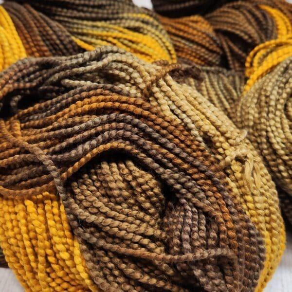 Skeins of yellow and brown yarn on a white surface.