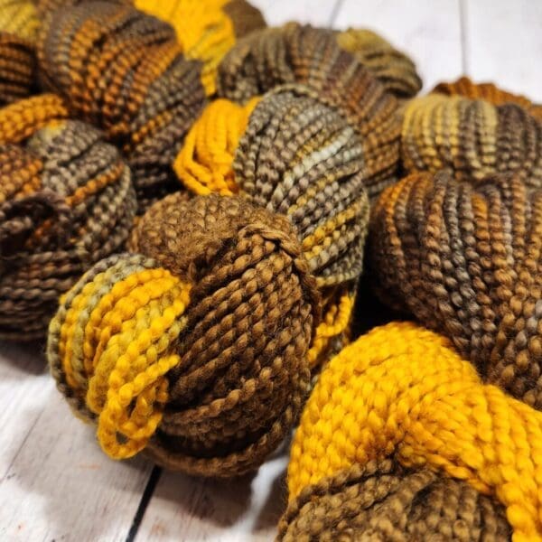 Skeins of brown and yellow yarn on a wooden table.