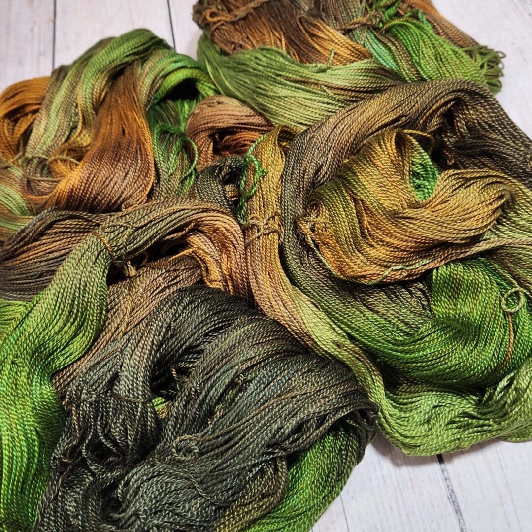 A bunch of green and brown yarns on a wooden table.