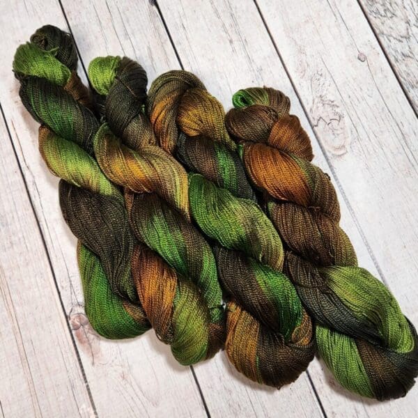 Three green and brown skeins on a wooden floor.