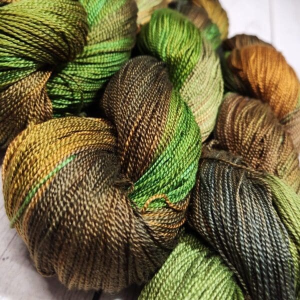 Skeins of green and brown yarn on a wooden table.
