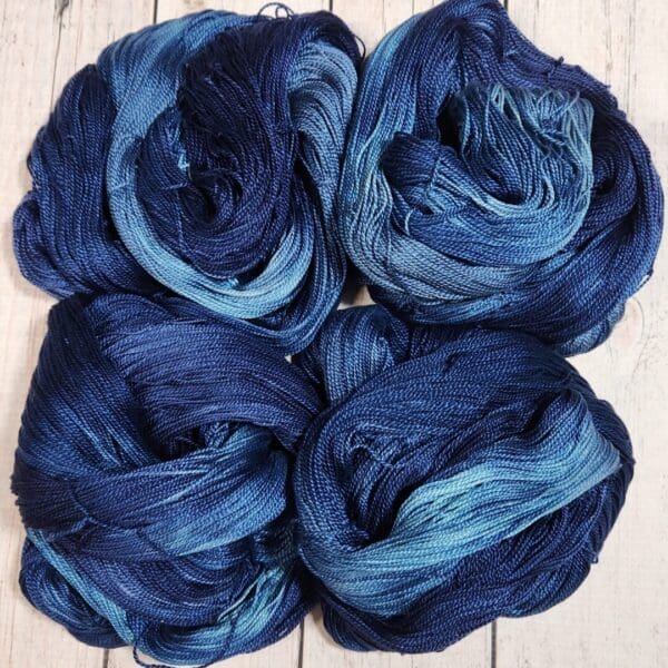 Four skeins of blue yarn on a wooden surface.