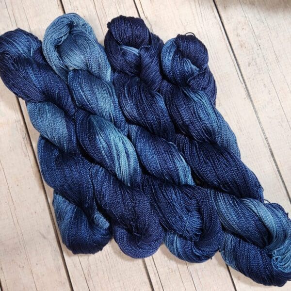 Three skeins of blue yarn on a wooden floor.