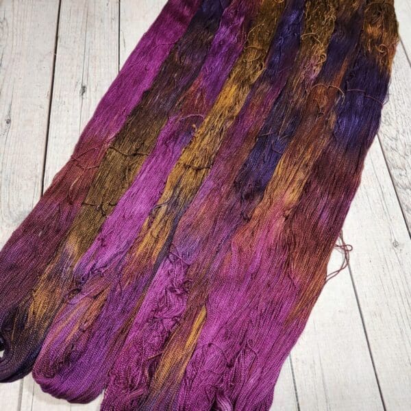 Purple and brown dyed yarn on a wooden floor.