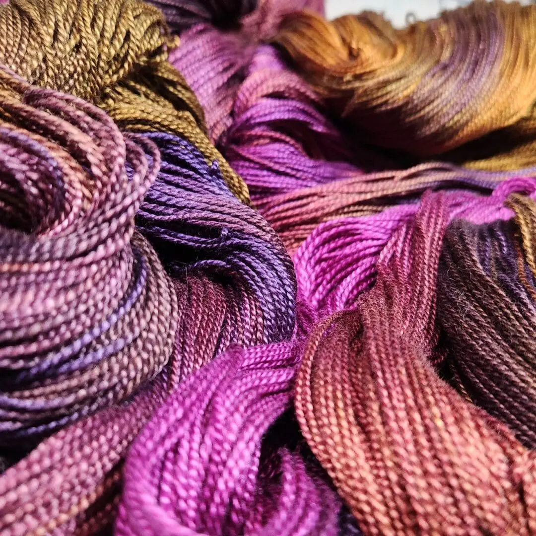 A close up of a bunch of different colored threads.