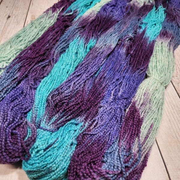 A skein of purple and blue yarn on a wooden table.