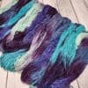 Skeins of purple, blue and green yarn on a wooden table.