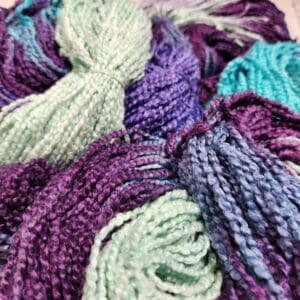 Skeins of purple, blue, and green yarn.