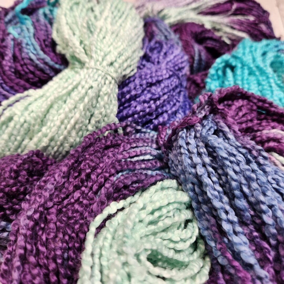 Skeins of purple, blue, and green yarn.