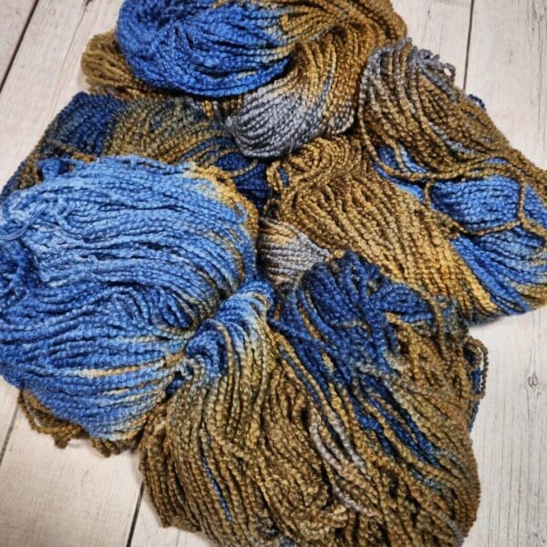A skein of blue and yellow yarn on a wooden table.