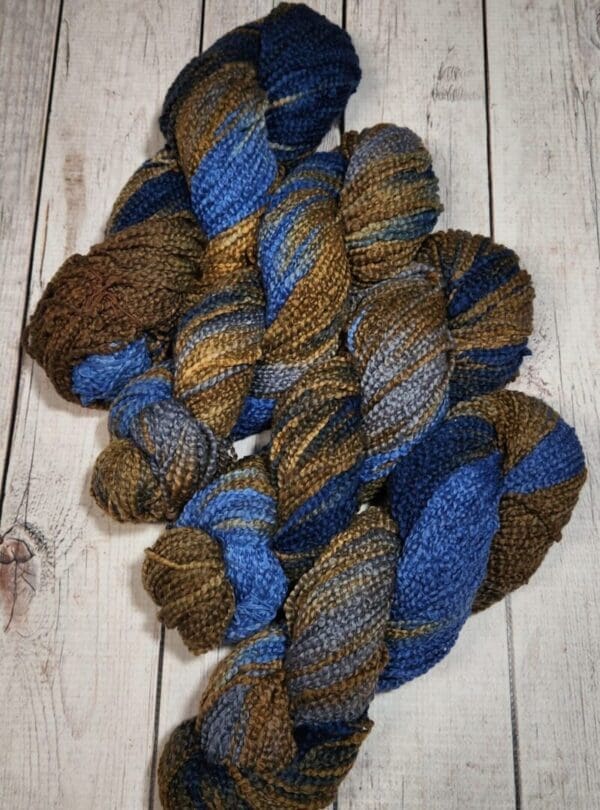 A skein of blue and brown yarn on a wooden table.