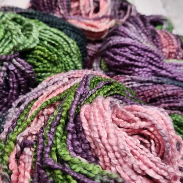 Skeins of yarn in purple and green colors.